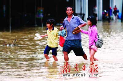 樂(lè)昌市政府前和街道被水浸,一位家長(zhǎng)帶著孩子涉水而行?！　」攘⑤x童銅韶朱裕超攝