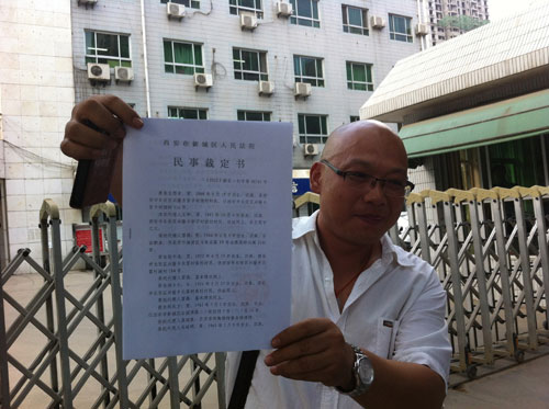 藥慶衛(wèi)代理人馬延明在法院門口向記者展示裁定書（來源：王甲鑄攝）