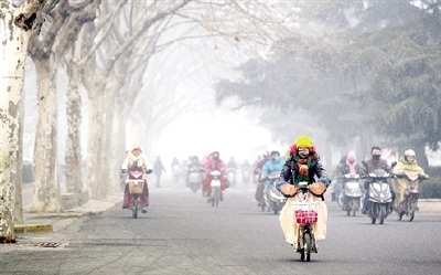 昨天上午，中原路，行人在霧霾中騎車(chē)出行，很多行人戴上了口罩。